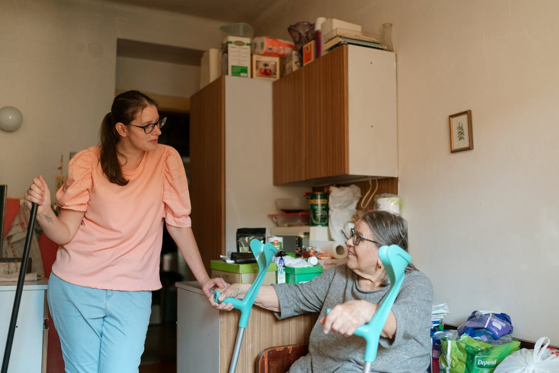 Caregiver assisting an elderly woman with crutches at home