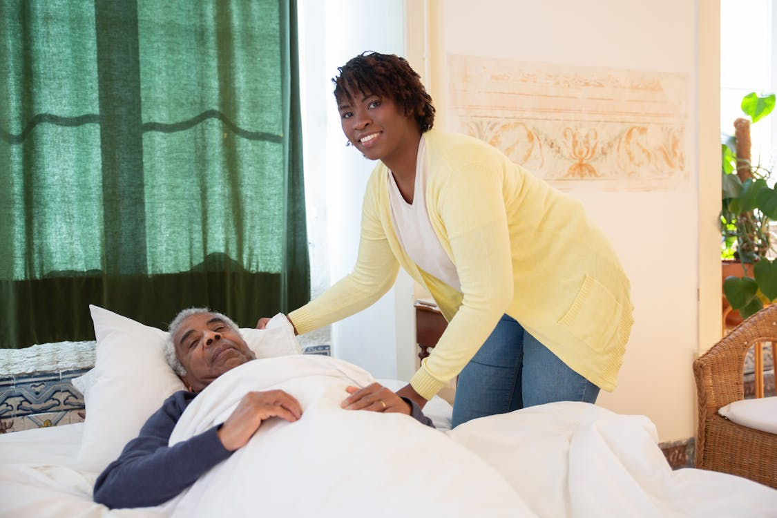 Caregiver smiling while assisting an elderly patient